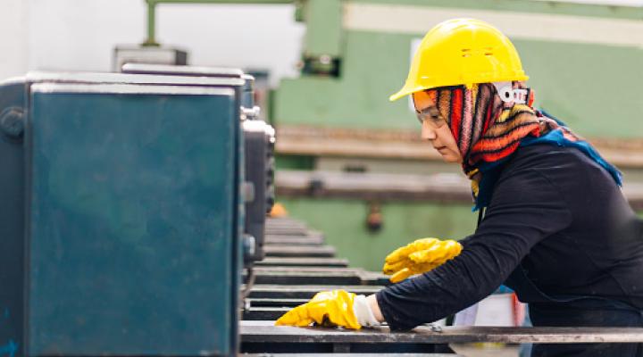 Muslim female worker working on cutting machine