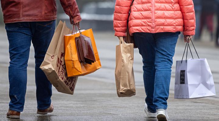 dos personas fotografiadas de espalda cargando bolsas de compras