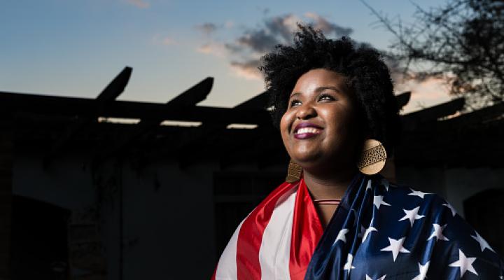 Una mujer negra, sonriente, envuelta en la bandera de EE.UU.