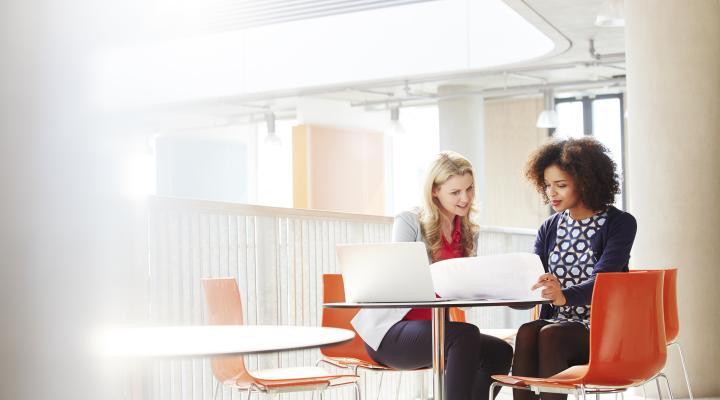 Dos mujeres de negocios hablando y mirando la misma computadora portátil