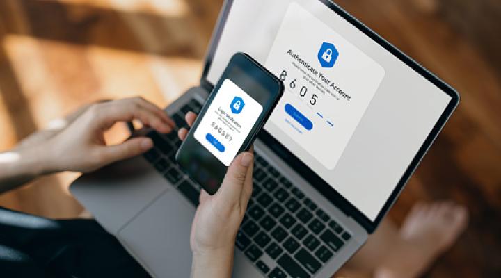 Cropped hand of woman using mobile device with Two-Factor Authentication (2FA) security while logging in securely to her laptop. 